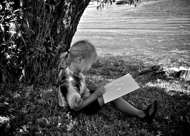 girl drawing a picture under a tree