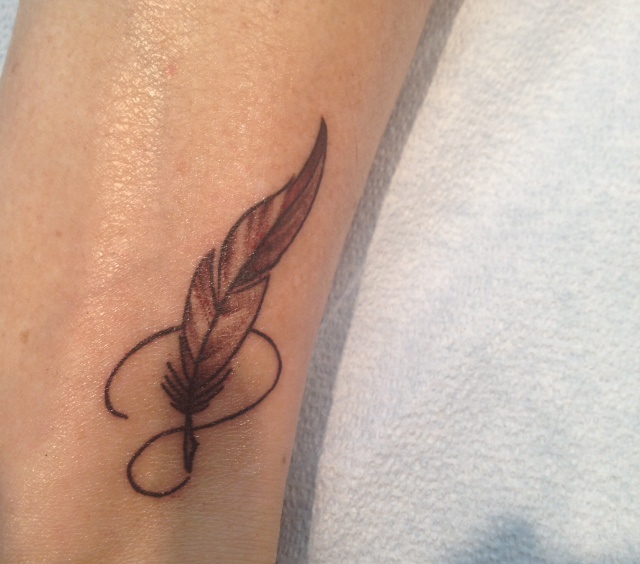 tattoo of quill pen on author's forearm
